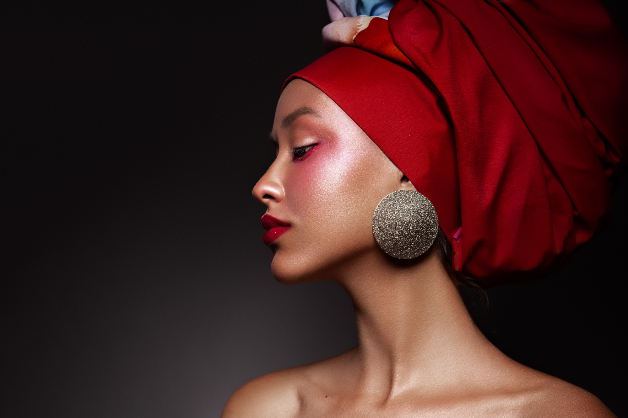 Portrait closeup Beauty fantasy african woman face in pink paint. Golden shiny skin. Fashion model